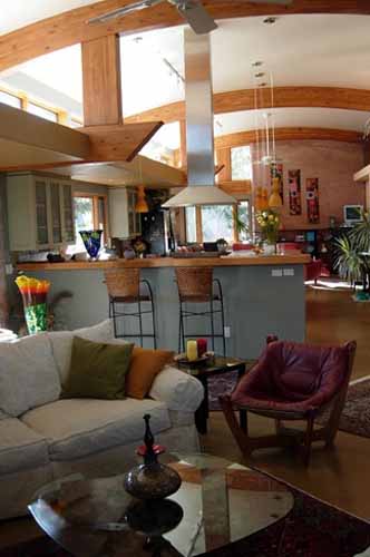 A well-lit great room featuring a vaulted ceiling with wooden beams